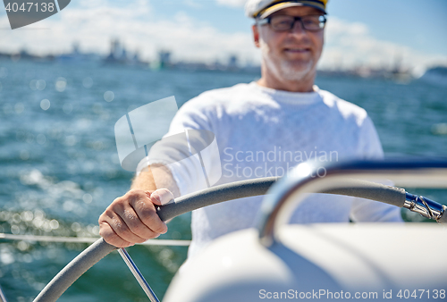 Image of senior man at helm on boat or yacht sailing in sea