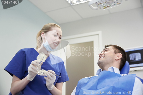 Image of happy dentist showing jaw layout to male patient