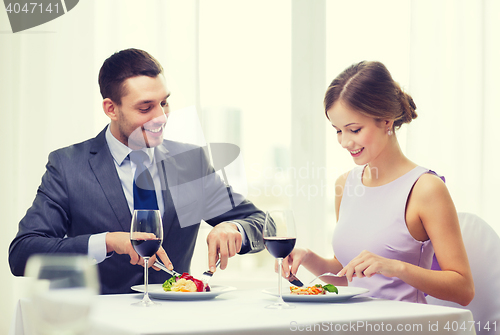 Image of smiling couple eating main course at restaurant