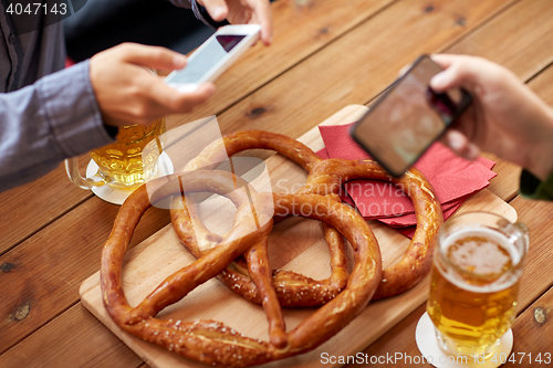 Image of close up of hands picturing pretzel by smartphone