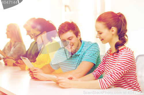 Image of smiling students looking at tablet pc at school