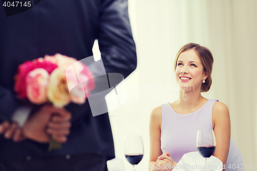 Image of young woman looking at man with flower bouquet