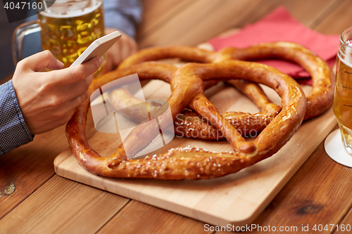 Image of close up of man with smartphone, beer and pretzels