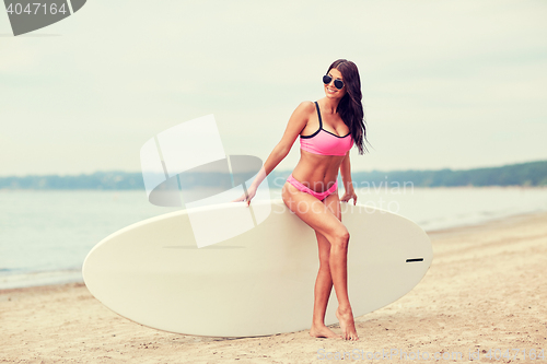 Image of smiling young woman with surfboard on beach