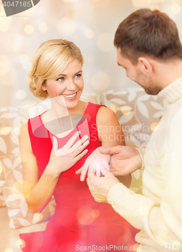 Image of romantic man proposing to a woman in red dress