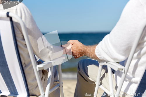 Image of senior couple sitting on chairs at summer beach