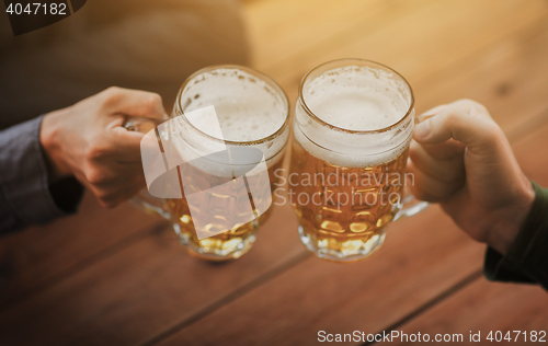 Image of close up of hands with beer mugs at bar or pub
