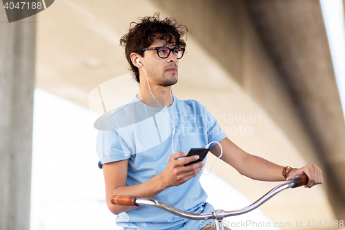 Image of man with smartphone and earphones on bicycle