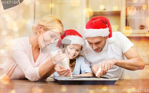 Image of happy family in santa helper hats making cookies