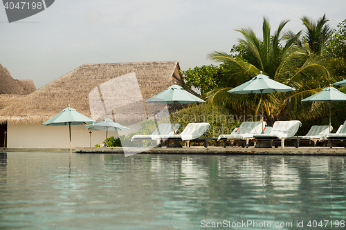 Image of parasol and sunbeds by sea on maldives beach