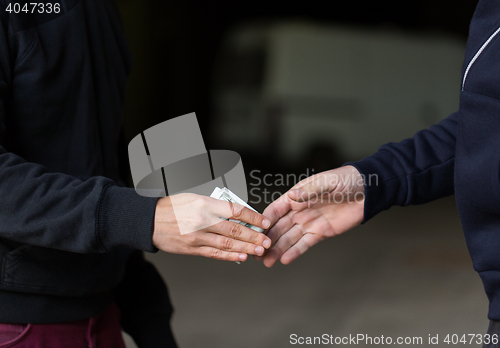 Image of close up of addict paying money to drug dealer