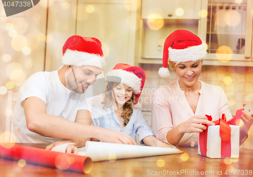 Image of smiling family in santa helper hats with gift box