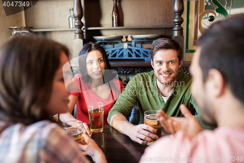 Image of happy friends drinking beer at bar or pub