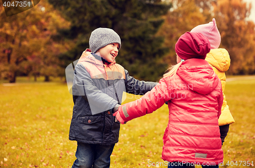 Image of children holding hands and playing in autumn park