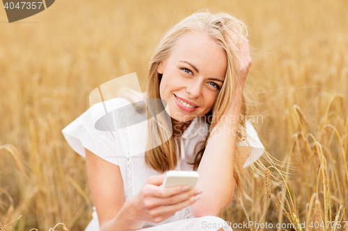 Image of happy young woman with smartphone on cereal field