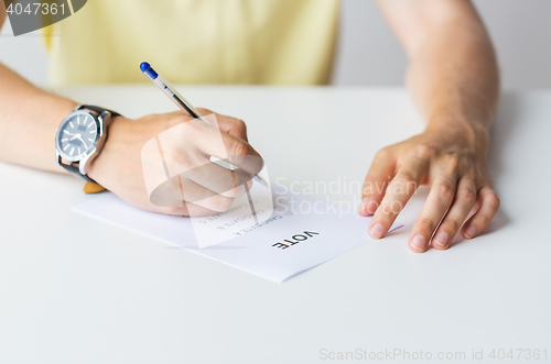 Image of close up of hands with vote or ballot on election