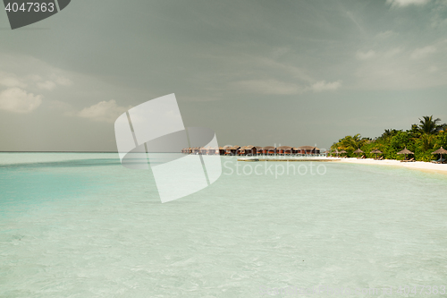 Image of bungalow huts in sea water on exotic resort beach