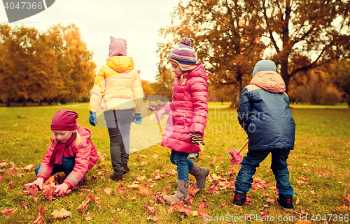 Image of group of children collecting leaves in autumn park