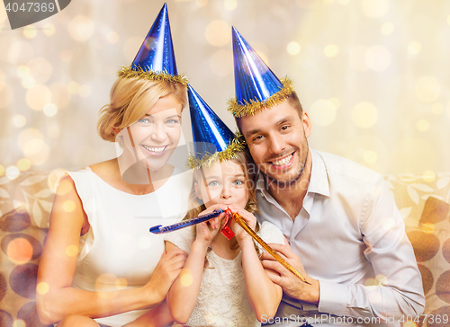 Image of smiling family in blue hats blowing favor horns