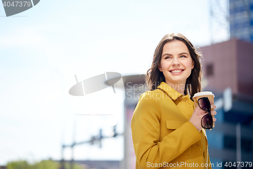 Image of happy young woman drinking coffee on city street