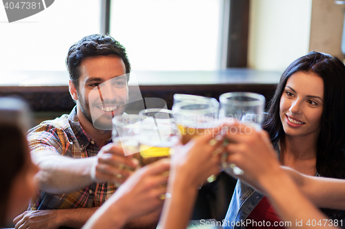 Image of happy friends drinking beer at bar or pub