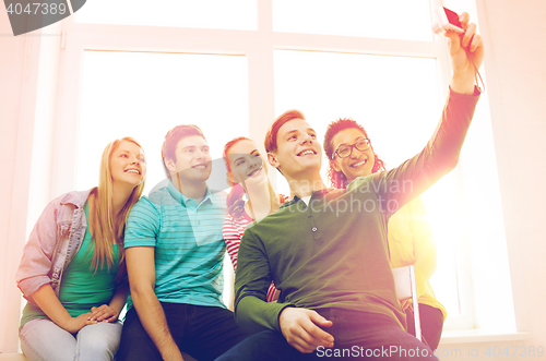 Image of five smiling students taking picture with camera