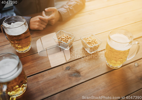 Image of close up of hands with beer mugs at bar or pub