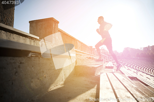 Image of happy young man running upstairs on stadium