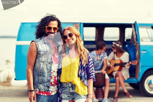 Image of smiling hippie couple with friends over minivan