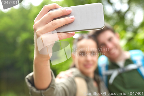 Image of couple with backpacks taking selfie by smartphone