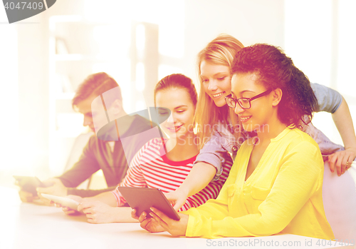 Image of smiling students looking at tablet pc at school