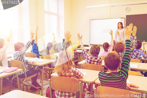 Image of group of school kids raising hands in classroom