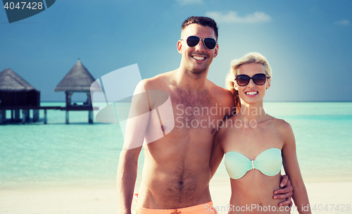 Image of happy couple in swimwear hugging on summer beach