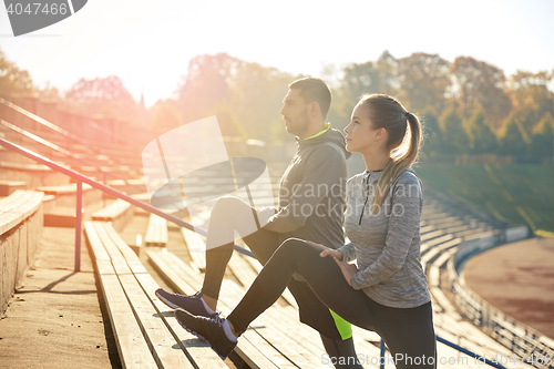 Image of couple stretching leg on stands of stadium