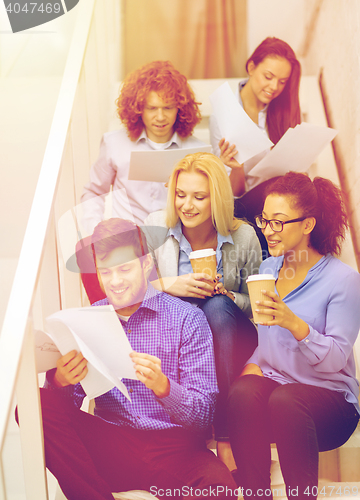 Image of team with papers and take away coffee on staircase