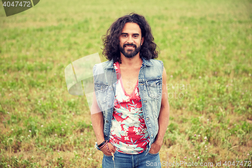 Image of smiling young hippie man on green field