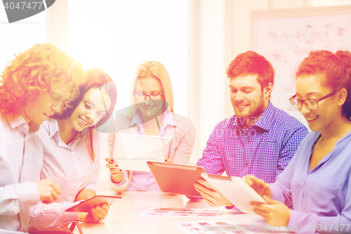 Image of smiling team with table pc and papers working