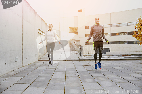 Image of man and woman exercising with jump-rope outdoors