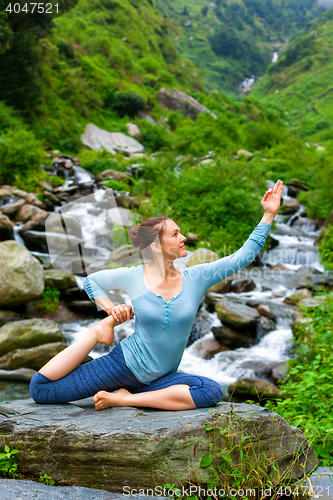 Image of Sorty fit woman doing yoga asana outdoors at tropical waterfall