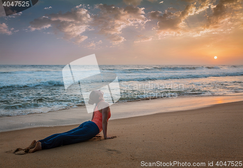 Image of Woman practices yoga asana Urdhva Mukha Svanasana at the beach