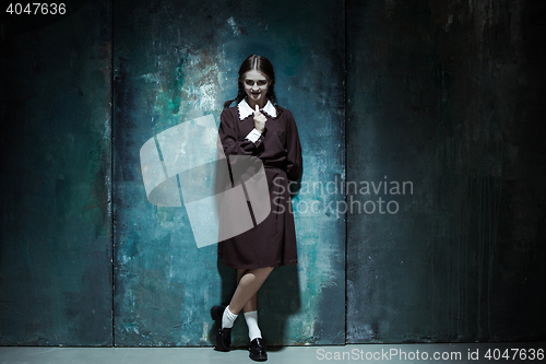 Image of Portrait of a young smiling girl in school uniform as killer woman