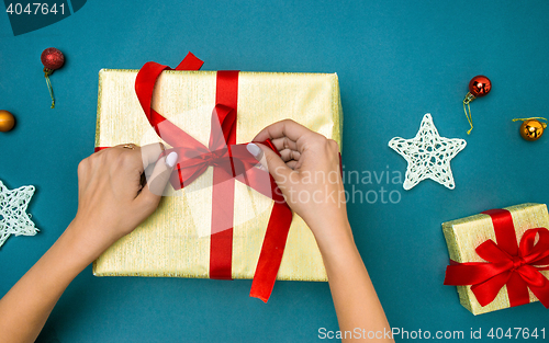 Image of Hands of woman decorating Christmas gift box.