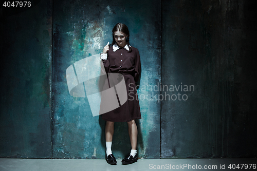Image of Portrait of a young smiling girl in school uniform as killer woman