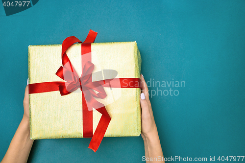 Image of Female hands holding gift on blue background