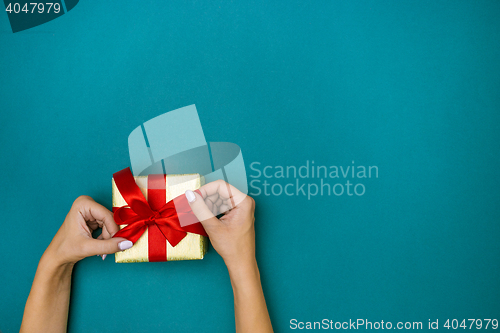 Image of Female hands holding gift on blue background