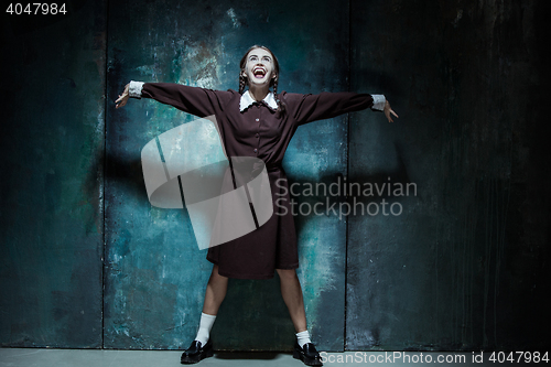 Image of Portrait of a young smiling girl in school uniform as killer woman