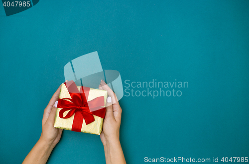 Image of Female hands holding gift on blue background