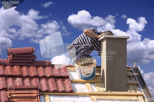 Image of Roofer builder worker repairing a chimney stack on a roof house