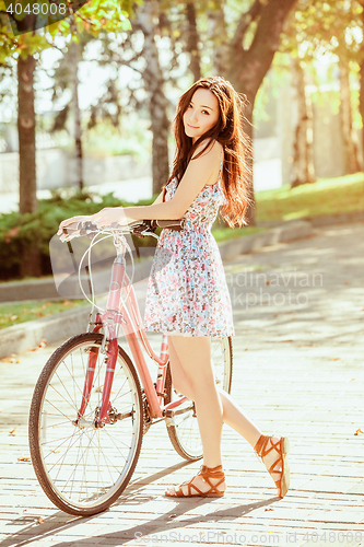 Image of The young girl with bicycle in park