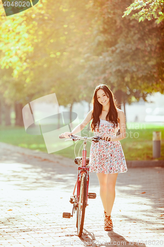 Image of The young girl with bicycle in park